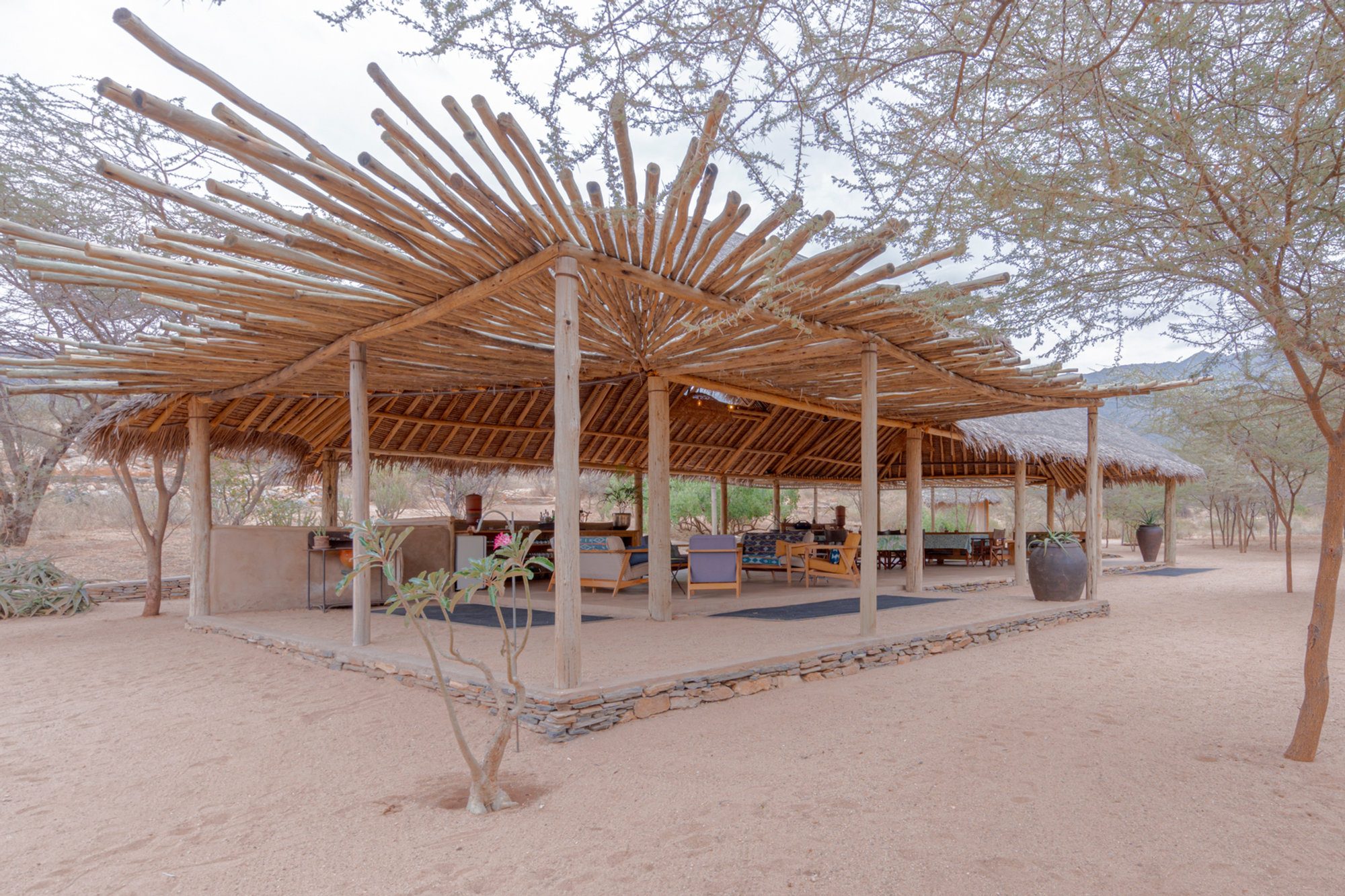 The open-sided thatched mess at Koros Camp under acacia trees